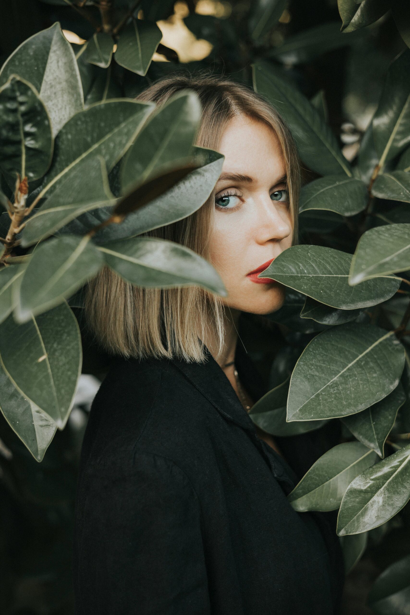 A captivating portrait of a woman with blonde hair surrounded by fresh green leaves in İstanbul.